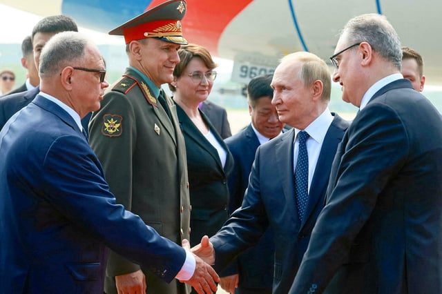 Le président russe Vladimir Poutine serre la main de responsables lors d'une cérémonie d'accueil à l'aéroport, à son arrivée pour le sommet de l'Organisation de coopération de Shanghai, le 31 août 2025. 
