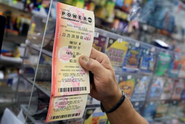 A customer holds a Powerball lottery ticket after purchasing it at the Downtown Miami Souvenirs store on August 26, 2025 in Miami, Florida.