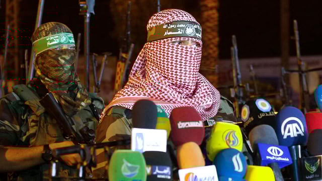 Das Bild aus dem Jahr 2015 soll den Hamas-Sprecher Abu Obeida zeigen, der sich vor Mikros äußert. Sein Gesicht ist durch ein weiß-rotes Palästinensertuch verhüllt.