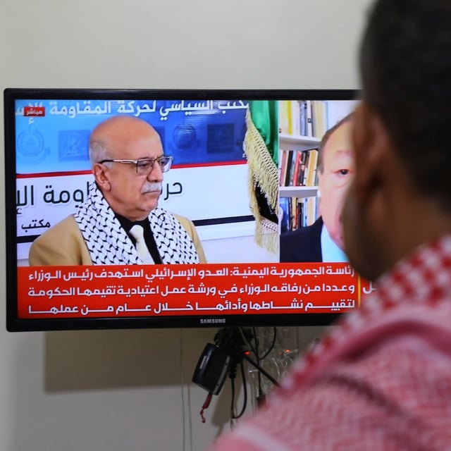 A man watches the news on TV, displaying footage of Ahmed al-Rahawi, the prime minister of the Houthi-controlled government, who was killed, along with others, in Thursday's Israeli strikes on the capital, in Sanaa, Yemen, Saturday, Aug. 30, 2025. (AP Photo/Osamah Abdulrahman)