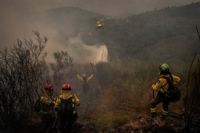 A helicopter from the Marroxo Brigade of Monforte de Lemos, makes a water drop directed by the group leader of BRICA (Special Reinforcement Brigade for Wildfires in Andalusia) from Granada, over a wildfire in Larouco, Lugo area, Galicia region, Spain, August 17, 2025. REUTERS/Mikel Konate//File Photo
