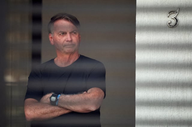 Brazil's former President Jair Bolsonaro stands at his home while under house arrest, ordered by Supreme Court Justice Alexandre de Moraes, as he awaits trial over an alleged plot to overturn the 2022 election, in Brasília, Brazil, August 14, 2025. REUTERS/Adriano Machado/File Photo