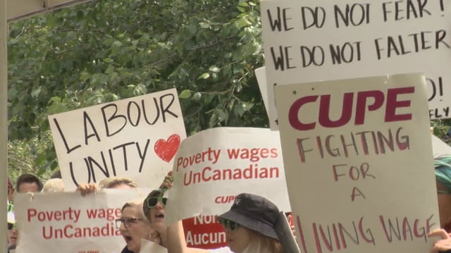 Members of the labour movement hold up signs. 