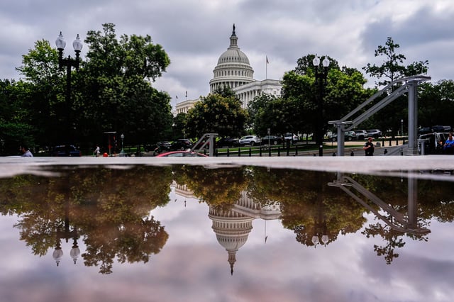 The US Capitol is reflected in a puddle outside of the Rayburn House Office Building, on July 16.