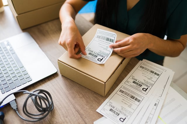 Stock image/file photo: A person labelling a package prior to shipment.