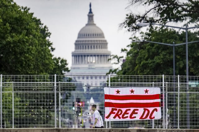 Pedestrians walk past a flag that reads "Free DC" hanging on an overpass near the U.S. Capitol building in Washington, DC, on Aug. 15, 2025.