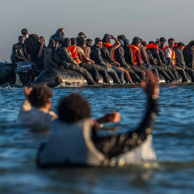 GRAVELINES, FRANCE - AUGUST 25: People gesture as they try to board a migrant dinghy into the English Channel on August 25, 2025 in Gravelines, France. Migrant crossings by boat have caused much controversy in the UK, with far-right groups organising demonstrations outside hotels housing migrants across the country over the summer. As of late August 2025, more than 28,000 migrants have crossed the English Channel in small boats this year. (Photo by Carl Court/Getty Images)