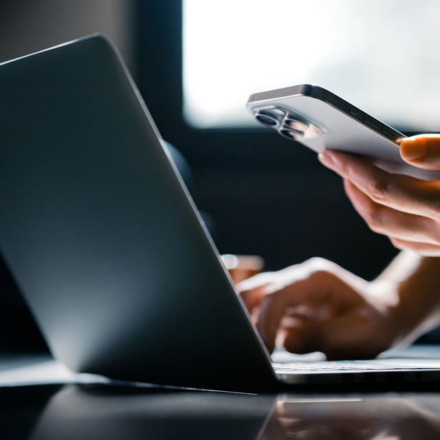 Close-up shot of a woman using mobile device with a Windows 11 laptop