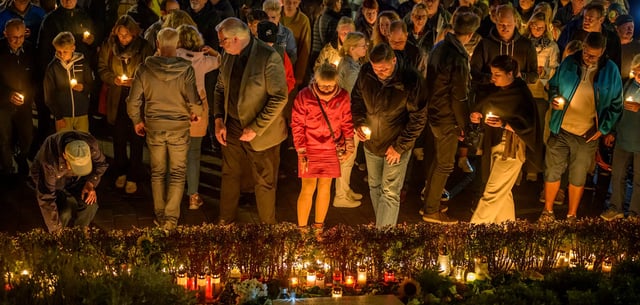 Ein Jahr nach dem Solinger Anschlag gedenken Menschen der Opfer und halten brennende Kerzen in den Händen