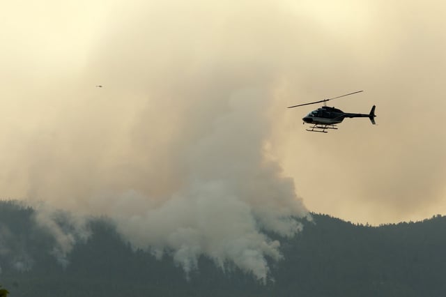 A helicopter flies by the Wesley Ridge wildfire near Cameron Lake where an out-of-control fire continues to burn near Coombs, B.C., Sunday, Aug. 3, 2025. THE CANADIAN PRESS/Chad Hipolito