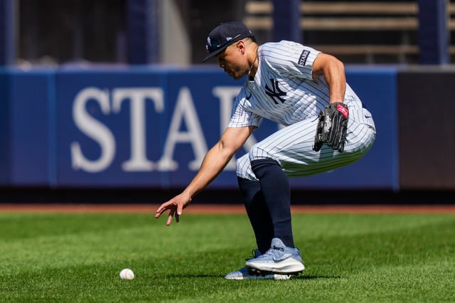 New York Yankees outfielder Giancarlo Stanton picks up a ball hit by Houston Astros' Jesús Sánchez (4) during the fourth inning of a baseball game against the Houston Astros, Saturday, Aug. 9, 2025, in New York. (AP Photo/Yuki Iwamura)