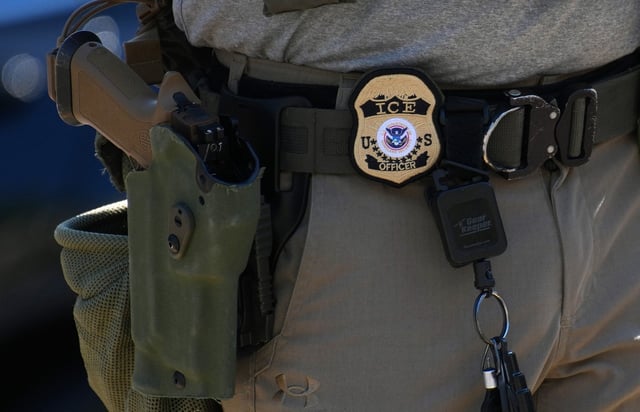 An Immigration and Customs Enforcement (ICE) officer's badge and weapon.