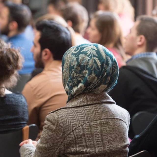 Flüchtlinge sitzen im Saal bei einem Sprachkurs.