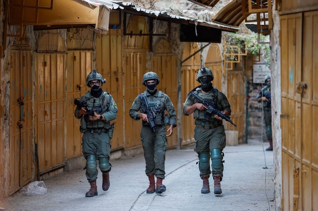 Israeli troops walk during a weekly settlers' tour in Hebron, in the Israeli-occupied West Bank, August 23, 2025. REUTERS/Mussa Qawasma