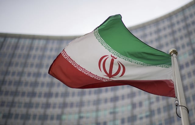 FILE - A national flag of Iran waves in front of the building of the International Atomic Energy Agency, IAEA, in Vienna, Austria, Friday, Dec. 17, 2021. (AP Photo/Michael Gruber, File)
