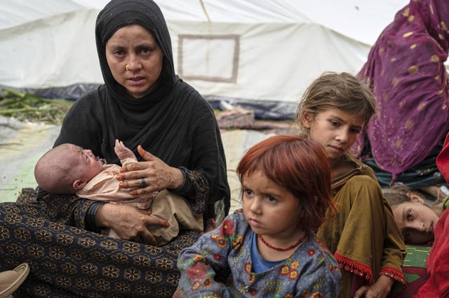 A woman and her children, survivors of Sunday night's 6.0-magnitude earthquake, wait for assistance in the village of Wadir, Kunar province, eastern Afghanistan, Tuesday, Sept. 2, 2025. (AP Photo/Nava Jamshidi)