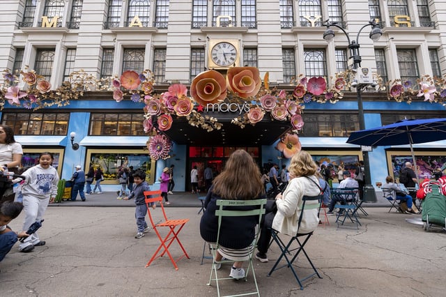 People are seen in front of the Macy's Herald Square store with flowers on display at the store entrance on May 15, 2025 in New York City.