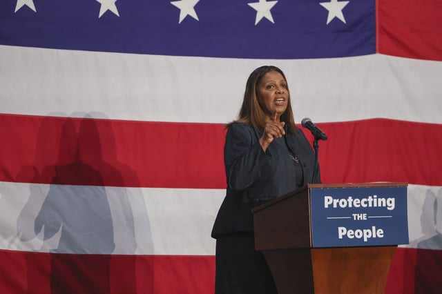 New York Attorney General Letitia James speaks at a podium in front of an American flag.