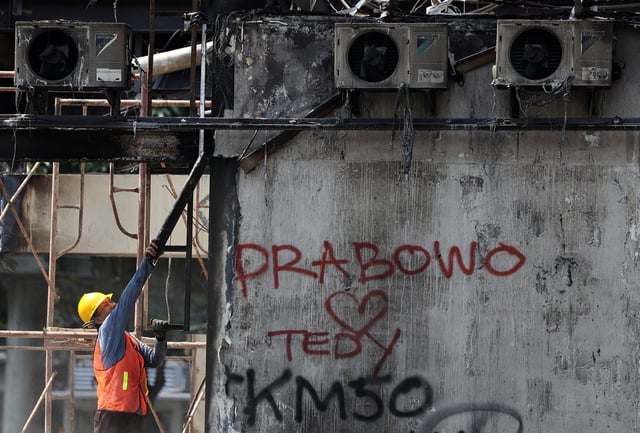 A municipality worker cleans debris at a burned bus stop following recent protest against police violence, which demonstrators say was brutal and violates human rights, after a rideshare driver was killed under a police tactical vehicle during a rally over parliamentarians' extra pay and housing allowances, in Jakarta, Indonesia, September 2, 2025. REUTERS/Willy Kurniawan/File photo
