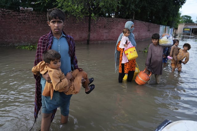 FILE - A family wades through flood waters to a rescue boat after levels in the Sutlej river rose following release of water from overflowing dams in neighboring India, in Kasur district, Pakistan, Aug. 26, 2025. (AP Photo/K.M. Chaudary, File)