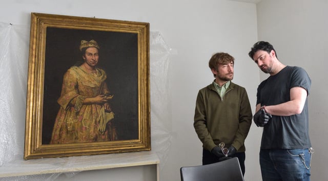 Visual arts teacher Ariel Bassano (L) stands next to a painting identified by Dutch newspaper AD as believed to be "Portrait of a Lady" by Italian baroque portraitist Giuseppe Ghislandi, stolen by the Nazis from a Dutch Jewish art collector, as it is displayed at the Public Prosecutor's Office in Mar del Plata, Argentina, on Sept. 3, 2025.(Stringer/AFP via Getty Images)