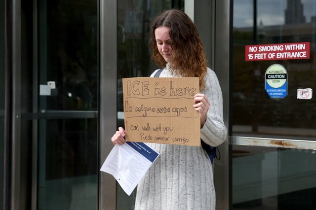Activist Rachel Cohen holds up signage outside Cook County's Domestic Violence Court branch, Sept. 3, 2025, to warn people arriving that ICE agents were reportedly inside the courthouse. (Antonio Perez/Chicago Tribune)