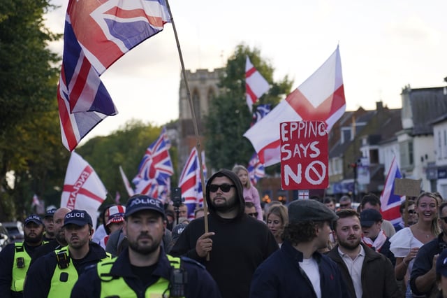 Police officers escort protesters near the Bell Hotel in Epping, London, Sunday, Aug. 31, 2025 after a temporary injunction that would have blocked asylum seekers from being housed at the hotel was overturned. (AP Photo/Alberto Pezzali)
