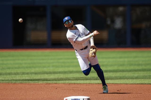 TORONTO, CANADA - AUGUST 31: Bo Bichette #11 of the Toronto Blue Jays makes a throw to first to try and beat out runner Jackson Chourio #11 of the Milwaukee Brewers in the first inning of their MLB game at Rogers Centre on August 31, 2025 in Toronto, Ontario, Canada. (Photo by Cole Burston/Getty Images)
