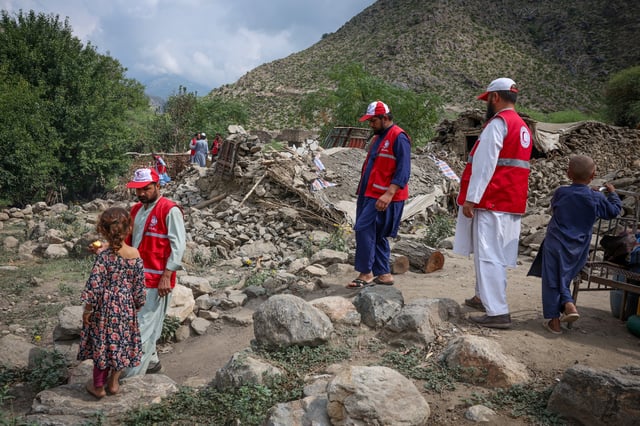 Red Crescent volunteers walk next to damaged houses as they reach Lulam village to help the victims following a deadly magnitude-6 earthquake that struck Afghanistan on Sunday, in Nurgal district, Kunar province, Afghanistan, September 3, 2025. REUTERS/Sayed Hassib