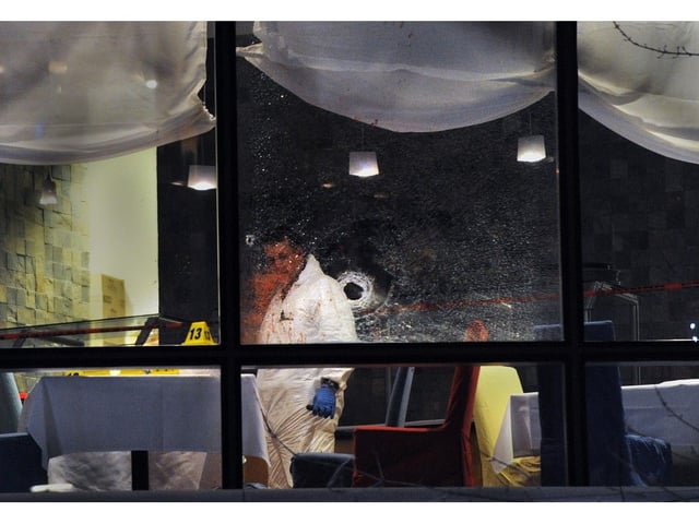  Police investigators look over an apparent bullet hole at the Sheraton Vancouver Wall Centre restaurant where Sandip Duhre was gunned down in January 2012