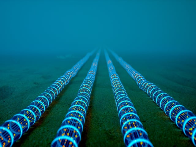High-tech fiber optic cables glowing with blue light extend into the distance on the ocean floor, symbolizing global communication networks.