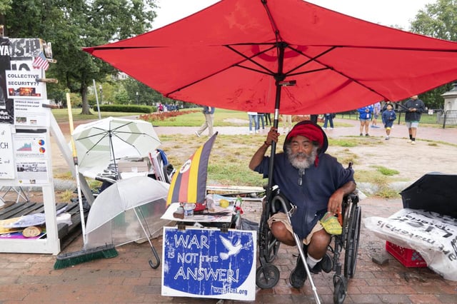 Philipos Melaku-Bello flashes the peace sign at the Peace Vigil in Lafayette Park across from the White House in Washington on Sunday. (JOSE LUIS MAGANA/AP)