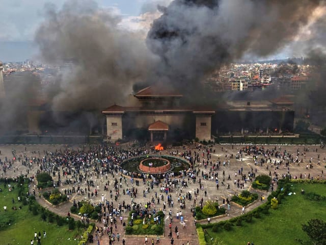 Protesters celebrate at the Singha Durbar, the seat of Nepal's government's various ministries and offices after it was set on fire during a protest against social media ban and corruption in Kathmandu, Nepal, Tuesday, Sept. 9, 2025. (AP Photo/Prakash Timalsina)