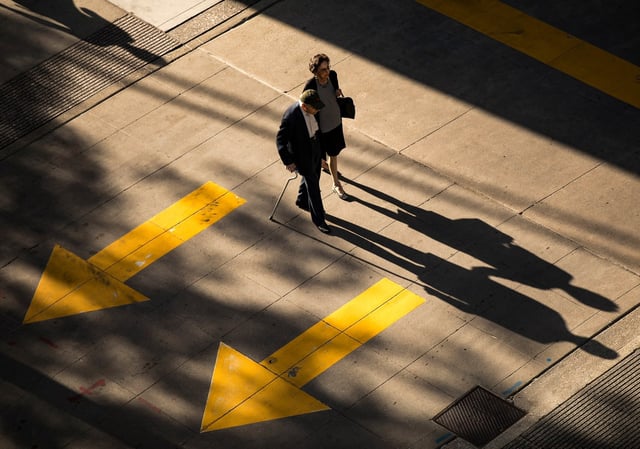 An elderly couple holds hands as they walk along East Huron Street in downtown Chicago. (Alyssa Pointer/Chicago Tribune)