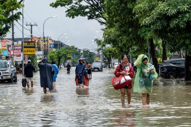 People carrying their belongings wade through a flooded street following overnight heavy rains in Legian, Badung, Bali, Indonesia September 10, 2025. REUTERS/Dicky Bisinglasi/File Photo