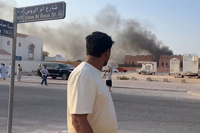 This frame grab taken from an AFPTV footage shows a man looking at smoke billowing after explosions in Qatar's capital Doha on September 9, 2025. An Israeli military official told AFP that the military had carried out air strikes on Doha on September 9 in an operation targeting senior leaders of Palestinian militant group Hamas.