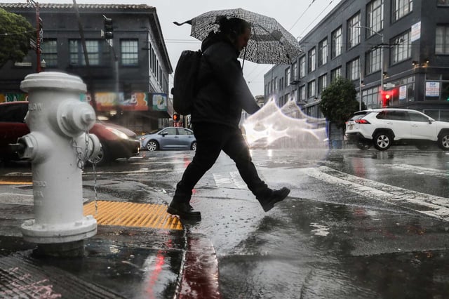 A pedestrian jumps over a flooded puddle in San Francisco on Feb. 4.