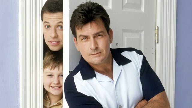 Jon Cryer and Charlie Sheen divided by a door.