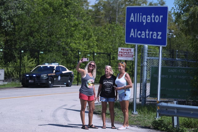 A group of women pose for a selfie in front of the "Alligator Alcatraz" sign at the entrance to an immigration detention center in the Florida Everglades, Thursday, Aug. 28, 2025, in Collier County, Fla. (AP Photo/Rebecca Blackwell)