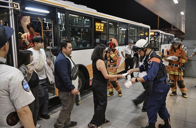 Passengers evacuated via emergency slides from a United Airlines Boeing 737 aircraft, heading to Cebu in the Philippines from Narita Airport near Tokyo, disembark from a bus at the Kansai airport in Izumisano, Osaka prefecture, western Japan September 12.