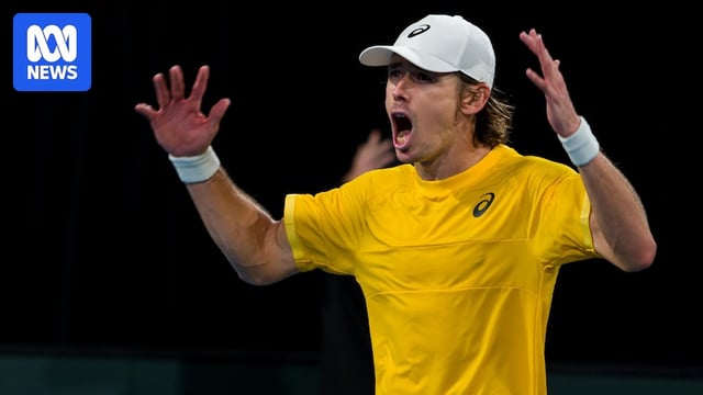 Alex de Minaur roars in celebration with both arms hoisted