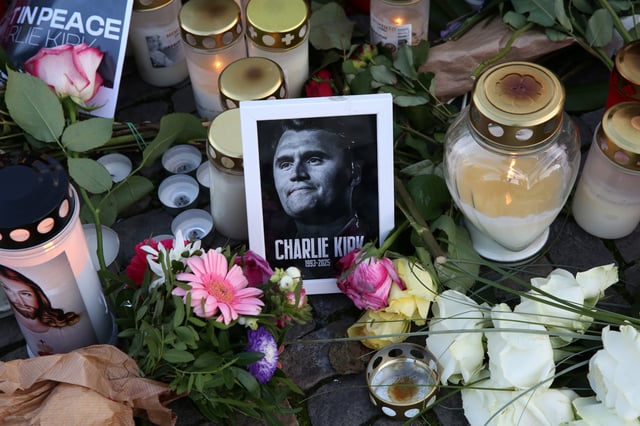Flowers and candles are seen at a makeshift memorial for murdered American conservative activist Charlie Kirk outside the U.S. embassy as its flag hangs at half-staff on September 14, 2025 in Berlin, Germany.