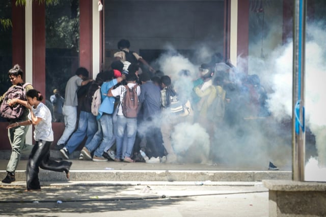 Protesting students run from tear gas fired by East Timor police