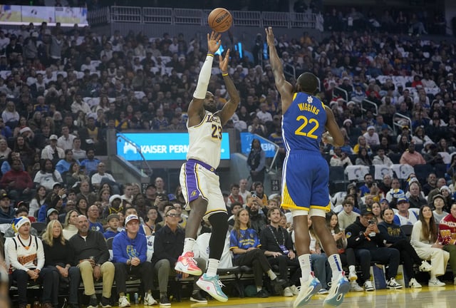 LeBron James #23 of the Los Angeles Lakers shoots over Andrew Wiggins #22 of the Golden State Warriors during the first half at Chase Center on December 25, 2024 in San Francisco, California.