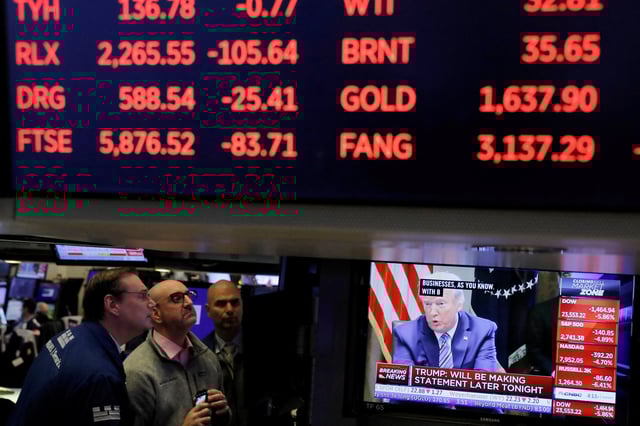 U.S. President Donald Trump is seen on a screen under trading figures on the floor of the New York Stock Exchange (NYSE) in New York City, New York, U.S., March 11, 2020. REUTERS/Andrew Kelly/File Photo