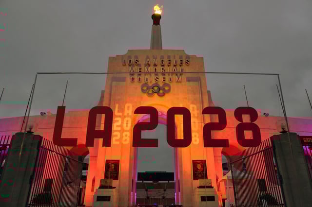 FILE – An LA 2028 sign is seen in front of the Olympic cauldron at the Los Angeles Memorial Coliseum, Wednesday, Sept. 13, 2017. (AP Photo/Richard Vogel, File)