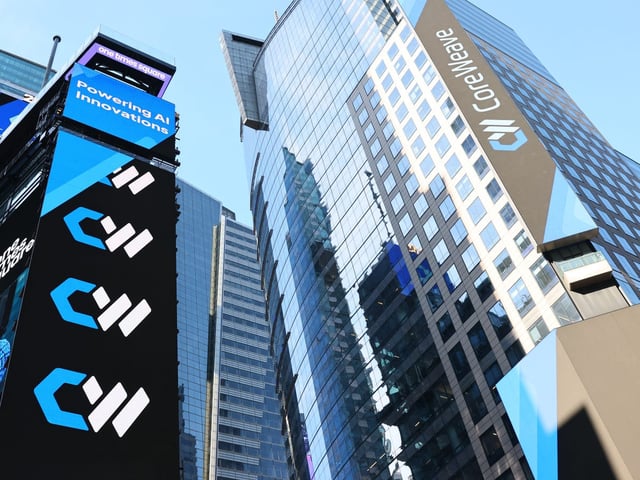 The CoreWeave company name and logo are displayed on digital billboards in Times Square during the company's IPO