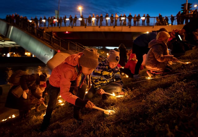 People participate in fire rituals during the Autumn Equinox celebration on the embankment of Neris river near King Mindaugas' Bridge in Vilnius, Lithuania, Friday, Sept. 20, 2019. Lithuanians celebrate equinox every year around  Sept. 20-22 when the day equates to night. Spectacular fire signs and music mystery play are held in Vilnius center at that time. The tradition began in 1992, but it is in accordance with the ancient pagan rituals and symbolize a victory of light against dark. (AP Photo/Mindaugas Kulbis)