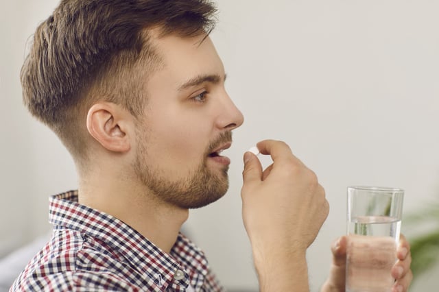 Young man taking pill.