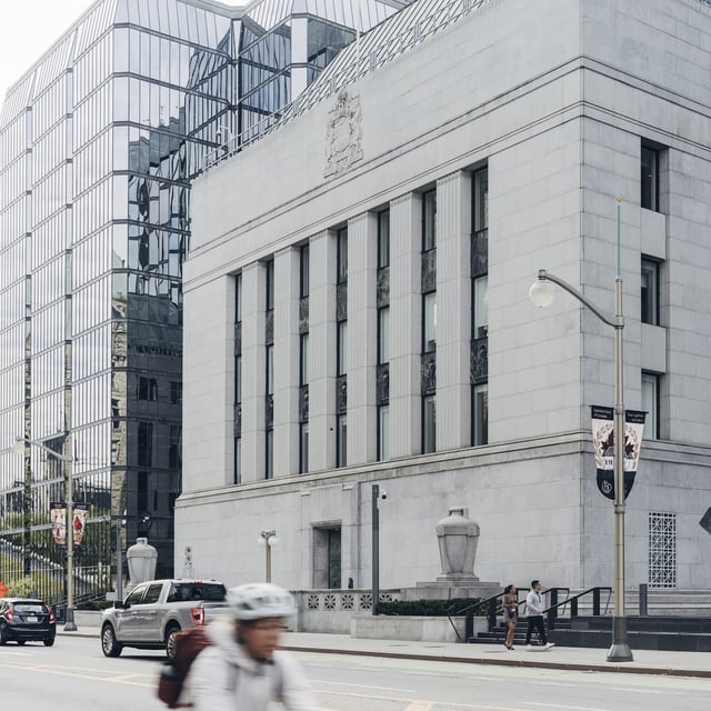 Commuters pass in front of the historic Bank of Canada building in Ottawa on an overcast morning, August 2025
